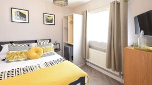 A hotel room with a bed, a desk, a chair, a television, and a window with curtains.