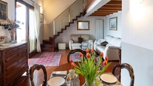 A dining area with a wooden table set for four, a vase with flowers, and a staircase leading to an upper floor. - ROMANTIC LAKE VIEW HOUSE (Sulzano)