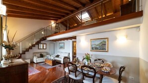 A spacious living area with a wooden staircase, a dining table set for four, and a sofa in the background. - ROMANTIC LAKE VIEW HOUSE (Sulzano)