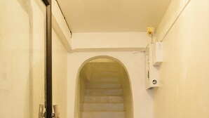 A narrow hallway with a glass door on the left and a staircase leading to an upper floor. - The Hidden Home (Patong)