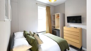 Una camera da letto moderna con un letto, un armadio, una televisione e una finestra con tende.