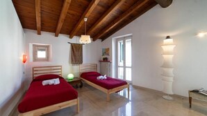 A room with two wooden beds, a ceiling fan, a small table, a lamp, and a window. - Duomo Apartment (Iseo)