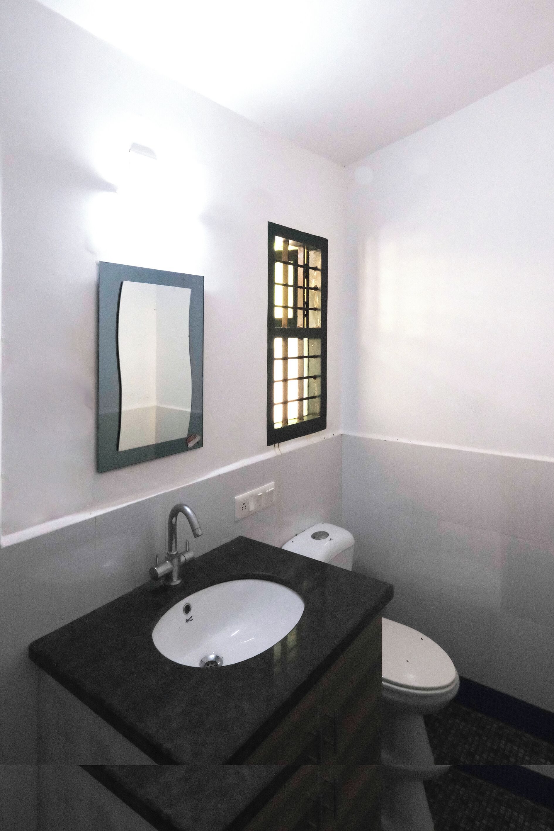 A bathroom with a white sink, a mirror, and a toilet.