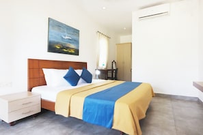 A hotel room with a bed, a nightstand, a desk, and a painting on the wall. - Lake Vechoor Villas (Vaikom)