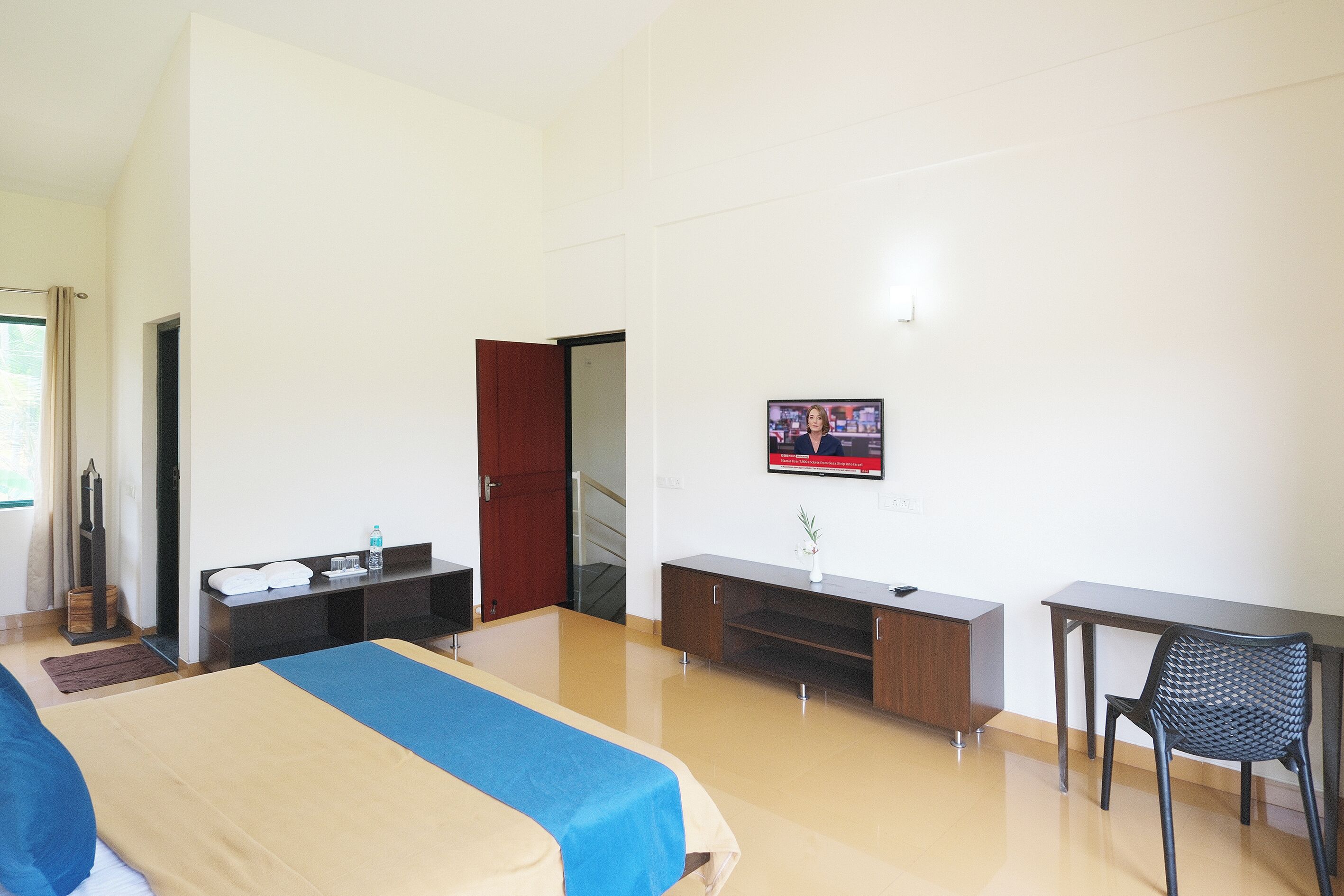 A hotel room with a bed, a desk, a chair, a TV, and a wardrobe.