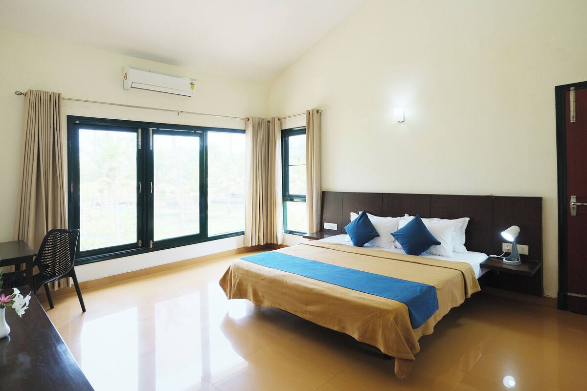 A hotel room with a bed, a desk, a chair, and a window with curtains.