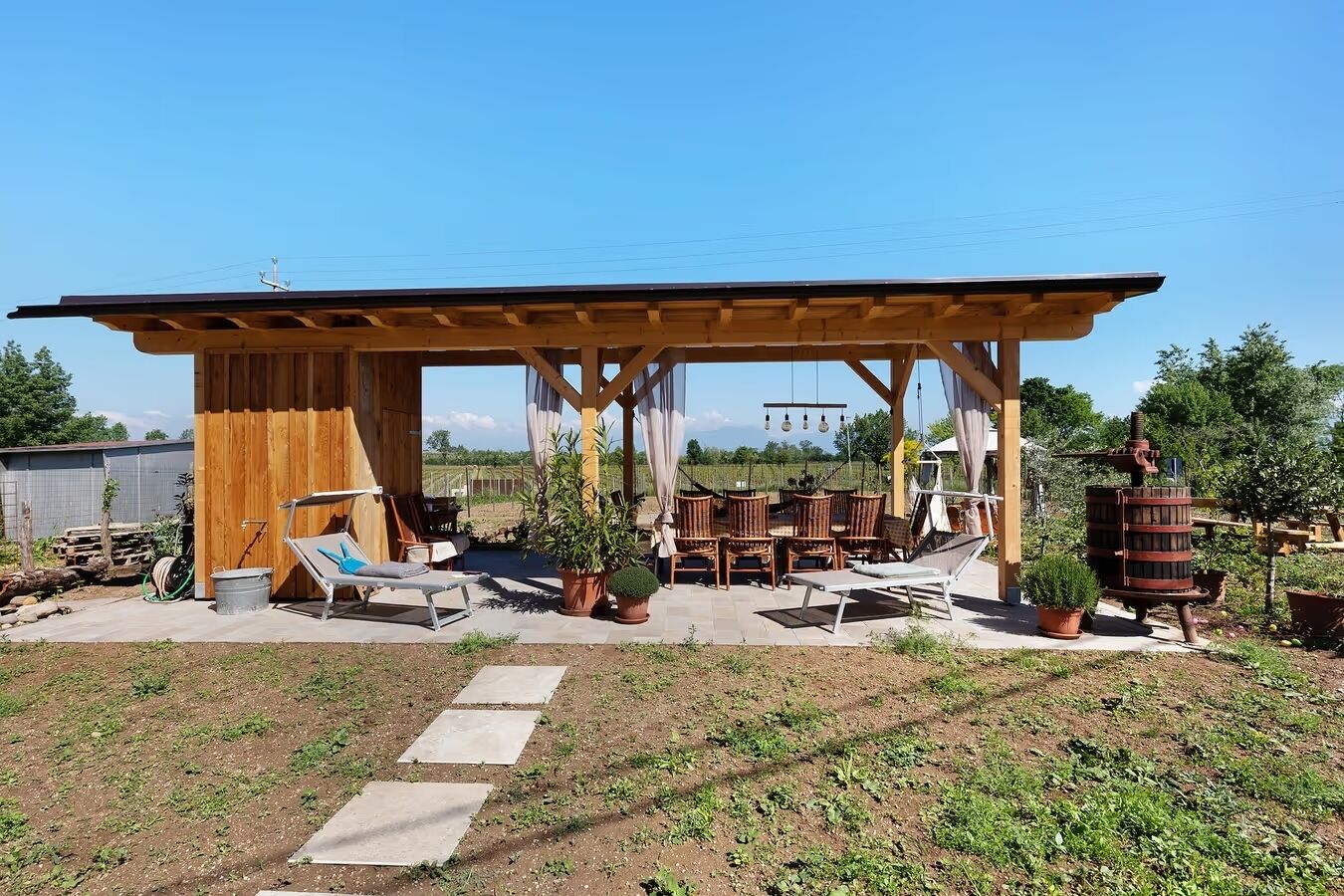 A covered outdoor patio with wooden furniture and potted plants.