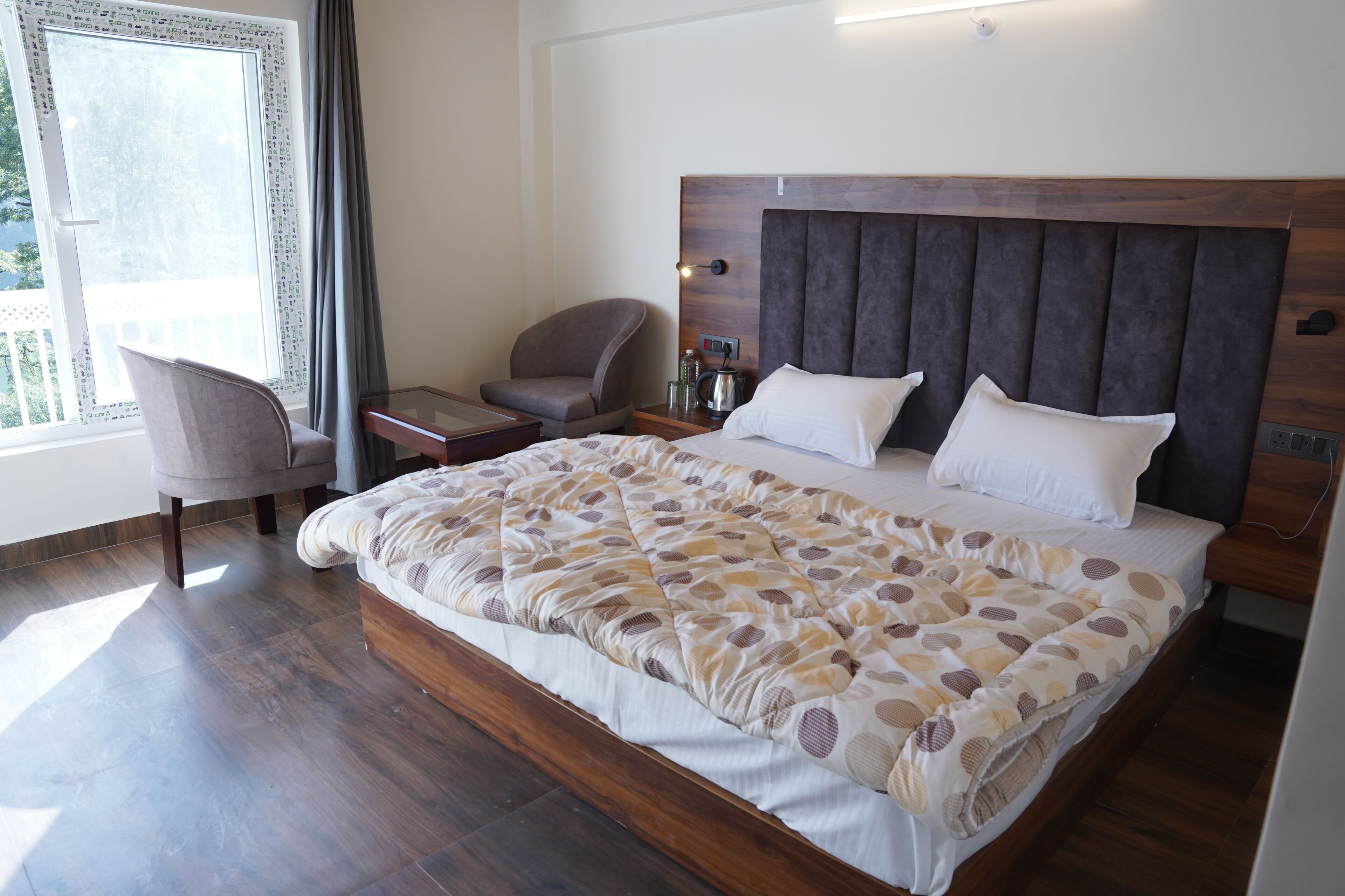 A hotel room with a large bed, a chair, a nightstand, and a window with curtains.
