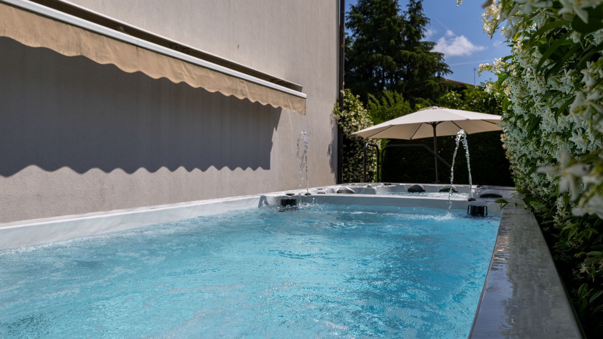 A swimming pool with a water fountain, surrounded by a covered patio area.