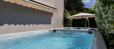 A swimming pool with a water fountain, surrounded by a covered patio area.
