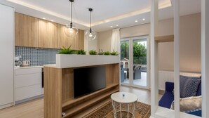 A modern kitchen with a TV, wooden cabinets, and a balcony with outdoor furniture. - Vila Oleander - Malinska by Villas Guide (Dobrinj)