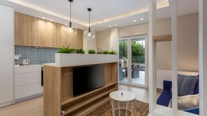 A modern kitchen with a TV, wooden cabinets, and a balcony with outdoor furniture.
