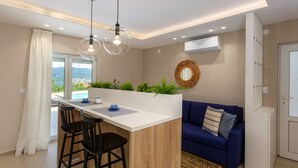 A modern kitchen with a central island, bar stools, a blue sofa, and a view of a cityscape. - Vila Oleander - Malinska by Villas Guide (Dobrinj)