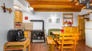 Una cucina accogliente con un camino a legna, un'area pranzo con mobili in legno e un piccolo frigorifero.