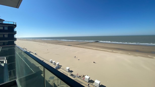 Une vue sur la plage depuis un immeuble de grande hauteur, avec un ciel dégagé.