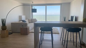 Un salon moderne avec un canapé, une table basse et un coin repas agrémenté d’un tabouret de bar.