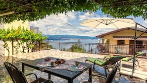 Un patio con mesa lista para dos personas, vista al mar y un edificio con balcón.