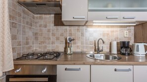 Une cuisine équipée d’une cuisinière à gaz, d’un évier en acier inoxydable et d’une machine à café.