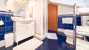 Ein Badezimmer mit einem weißen Waschbecken, blauen Fliesen, einer Holztür und einer Duschkabine aus Glas.