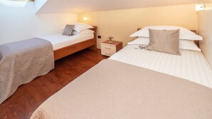 Ein Schlafzimmer mit zwei Betten, einem Nachttisch und einem kleinen Tisch mit einer Vase.