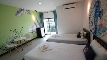 A hotel room with two beds, a small table, two chairs, and a window with curtains.
