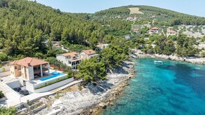 A coastal property with a swimming pool, multiple buildings, and a clear blue sea. - Villa Welcome by Villas Guide (Blato)
