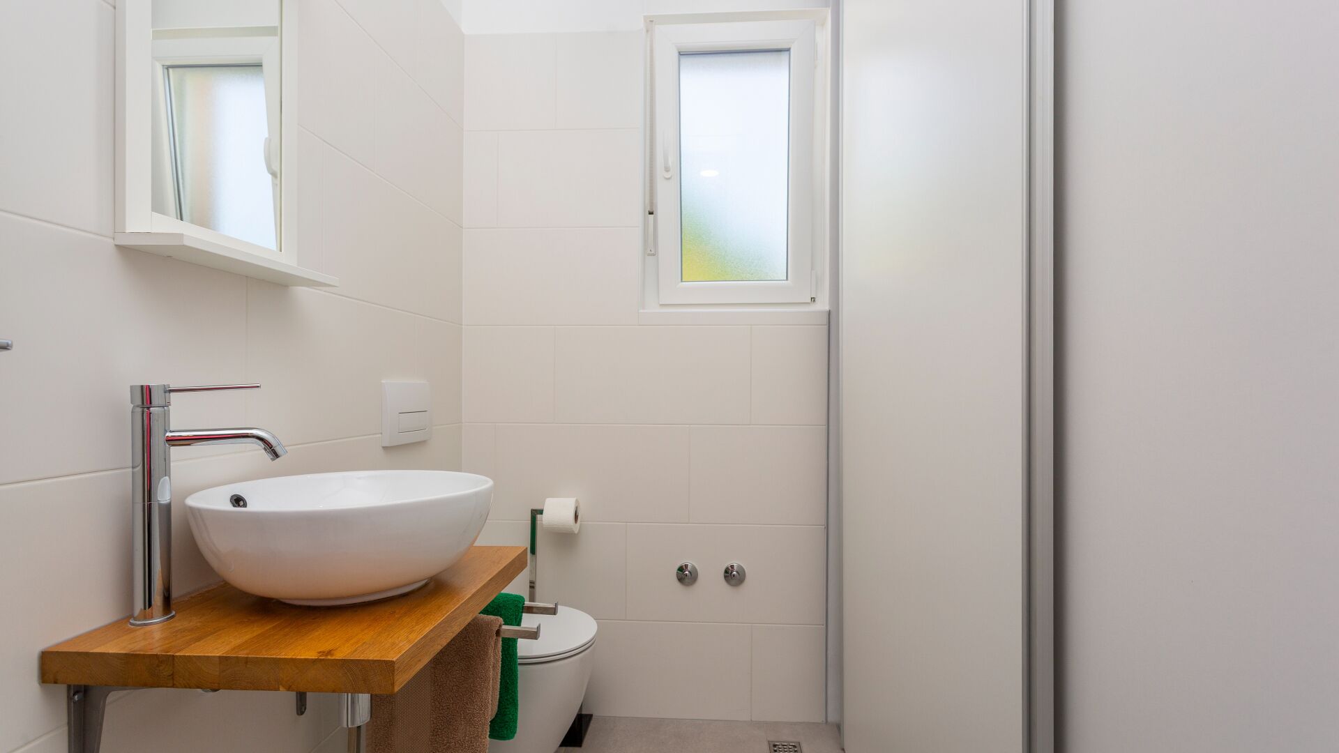 Ein Badezimmer mit Waschbecken, Spiegel, Fenster und Toilette.