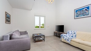 Una sala de estar con un sofá, una mesa de centro, un mueble para televisión y una ventana.