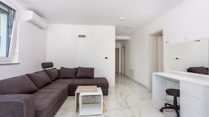 A modern living room with a sectional sofa, a small white coffee table, a white console table, and a large mirror.