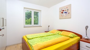 Un dormitorio con cama, ventana, mesita de noche y una obra de arte colgada en la pared.