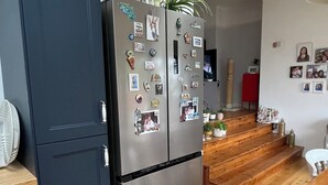 A modern kitchen with a dark blue cabinet, a stainless steel refrigerator, and wooden flooring. - 3 Bedroom Home at Hove with Garden & Cats (Brighton and Hove)