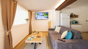 Un salón acogedor con un sofá, una mesa de centro y un televisor que muestra un paisaje tropical.