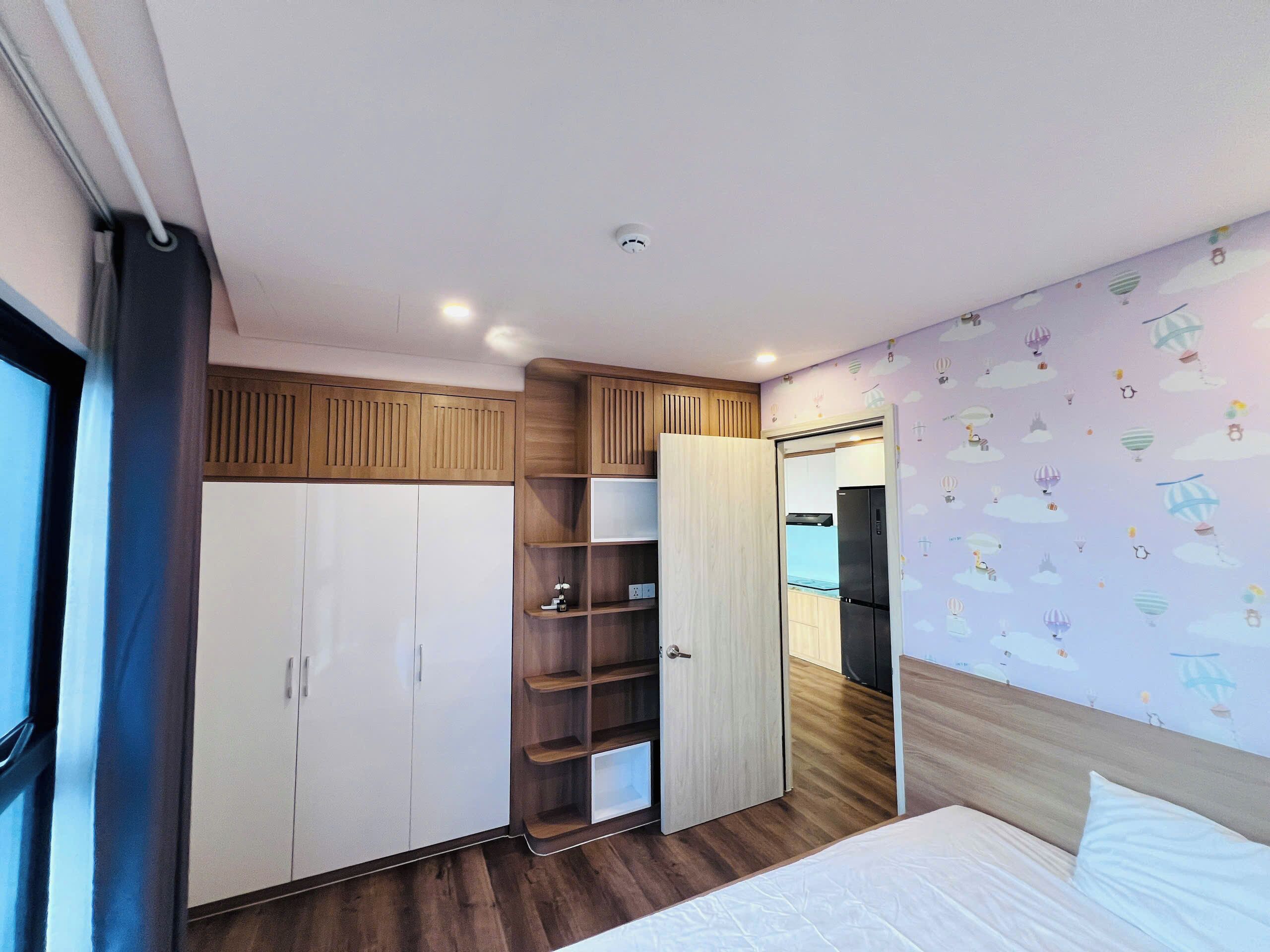 Une chambre à coucher comprenant un lit, une armoire et des étagères intégrées.