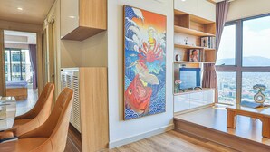 Quarto de hotel moderno com uma pintura grande, móveis de madeira e vista para a cidade.