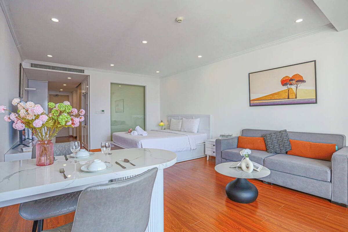 Une chambre d’hôtel moderne comprenant un coin repas, un lit, un canapé et un tableau au mur.