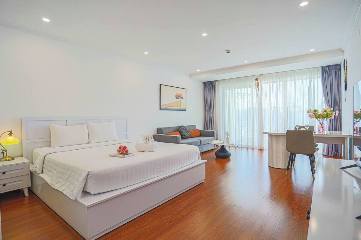 Une chambre d’hôtel moderne équipée d’un grand lit, d’un bureau, d’un canapé et d’un coin repas.