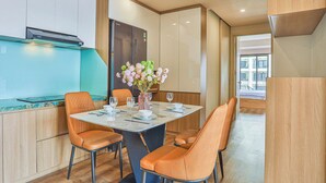 Uma área de refeições moderna com uma mesa central, cadeiras cor de laranja e um vaso de flores.