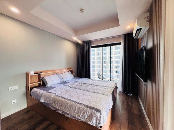 Una camera d'albergo moderna con un grande letto, una televisione a schermo piatto e vista sulla città attraverso la finestra.