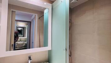 A bathroom with a marble sink, a mirror, and a shower.