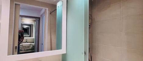 Une salle de bain avec un lavabo en marbre, un miroir et une douche.