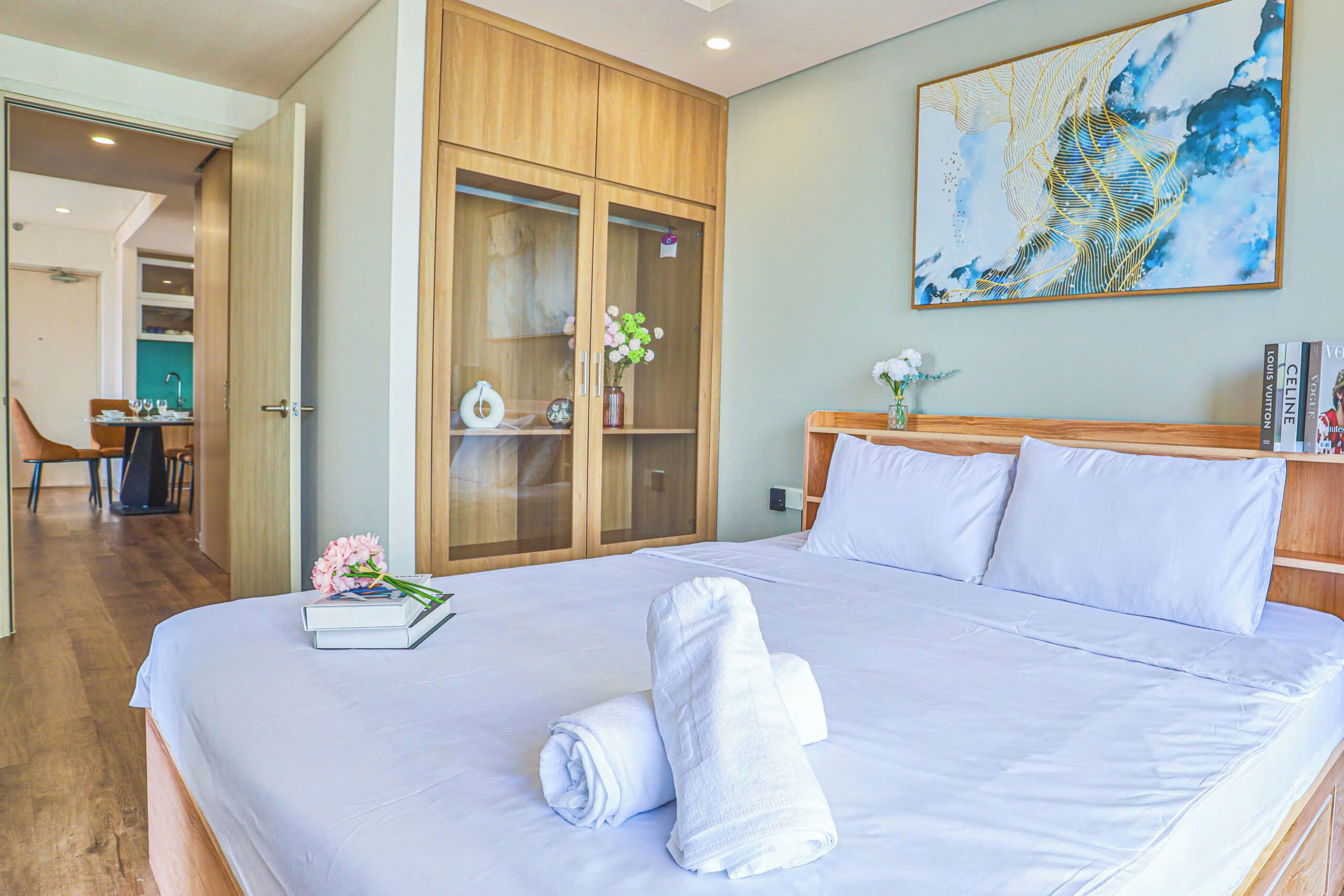 Una camera d'albergo con un letto grande, un armadio in legno, una scrivania con una sedia e un quadro appeso al muro.