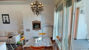 A dining area with a glass table, clear chairs, and a chandelier. - PROMENADE Luxury View (Sarnico)