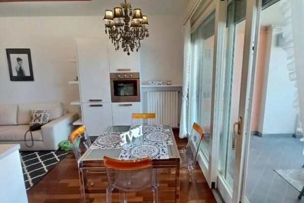 A dining area with a glass table, clear chairs, and a chandelier.