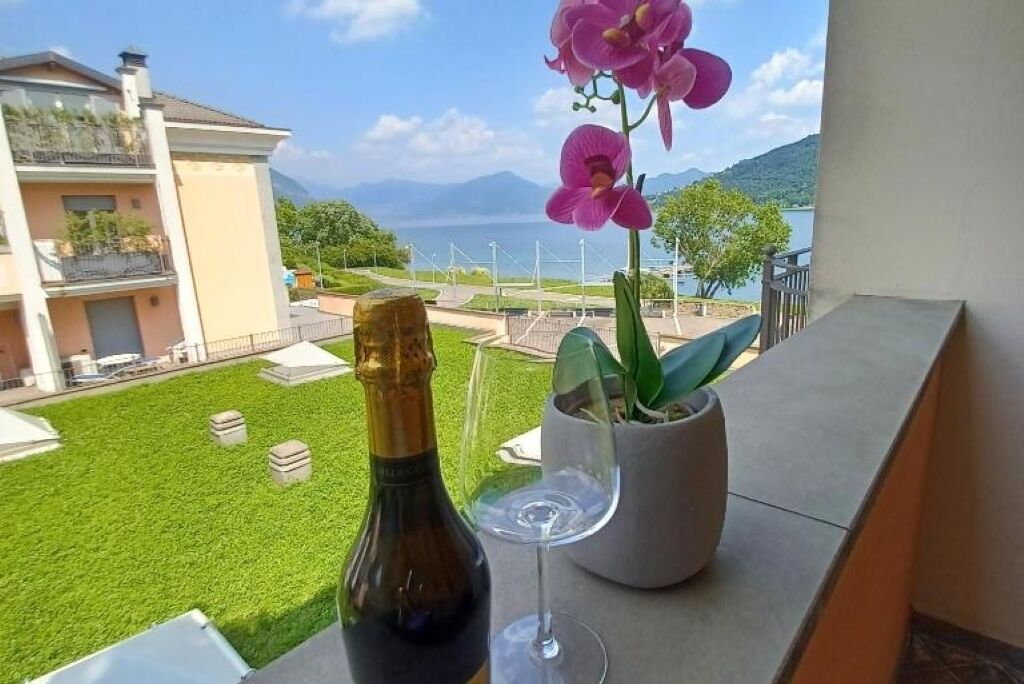 Een balkon met een fles wijn, een glas en een potorkidee.