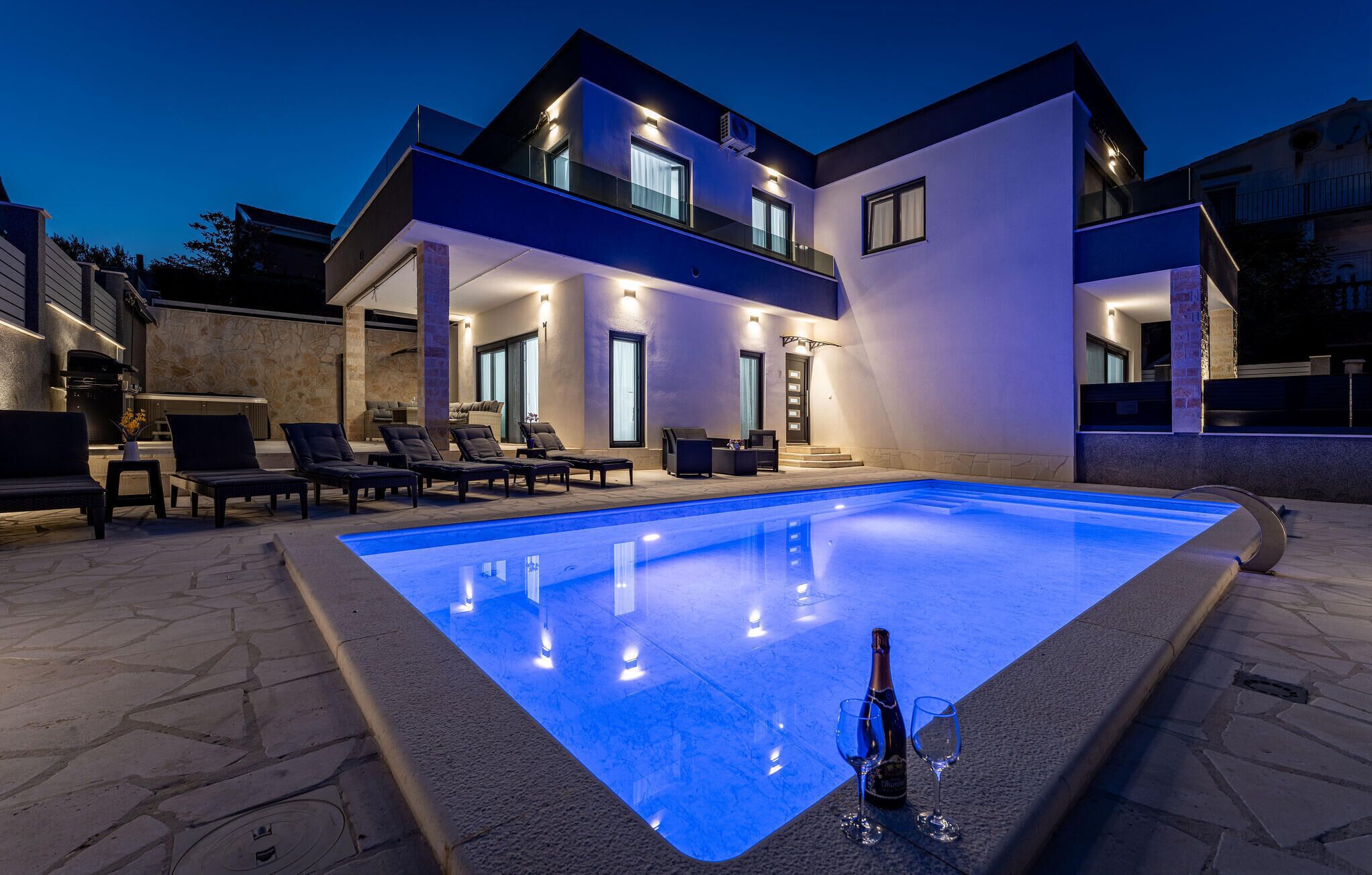 Een modern herenhuis met zwembad, terras en een goed verlichte entree.