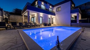 A modern two-story house with a swimming pool, outdoor seating, and a well-lit entrance. - Nice home in Pridraga (Pridraga)