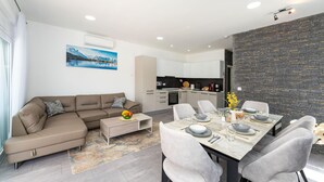A modern living room with a sofa, coffee table, and dining area with chairs and a table set for four. - Nice home in Pridraga (Pridraga)