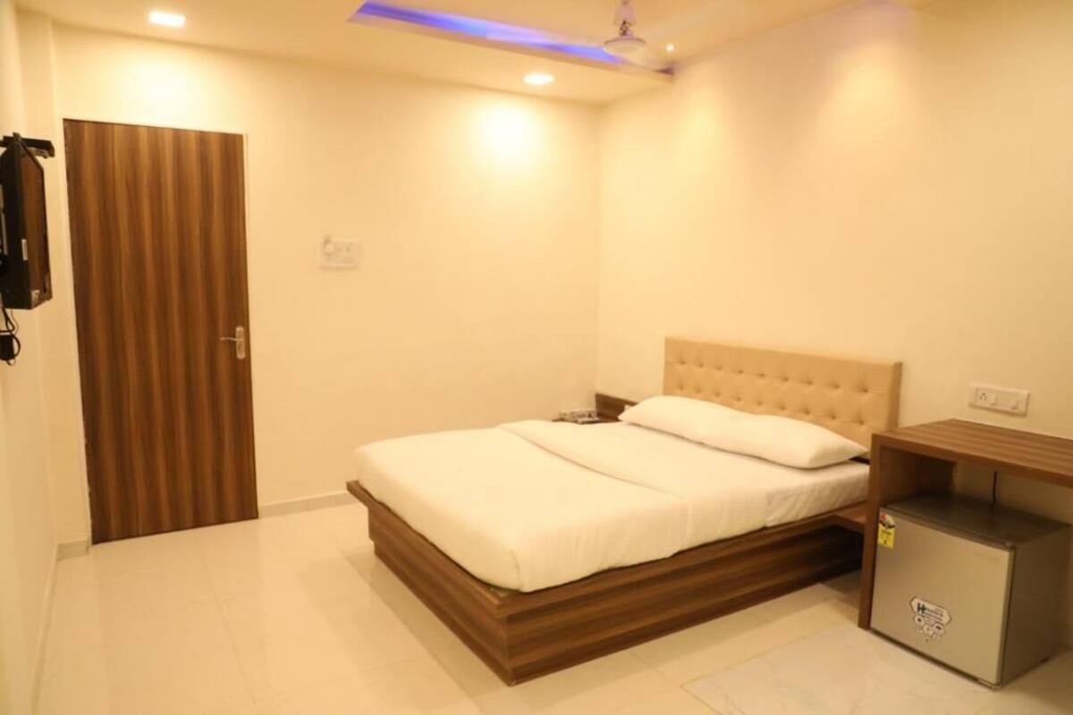 A bedroom with a bed, a wooden headboard, a nightstand, and a small refrigerator.