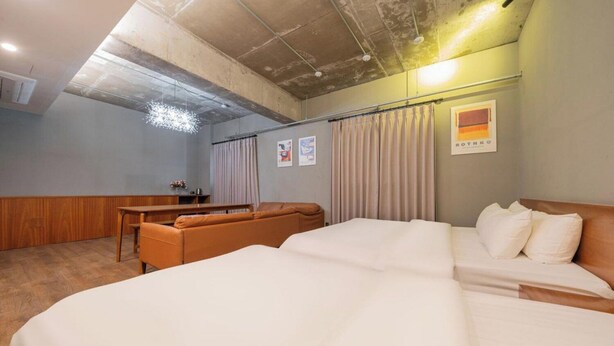 Ein Hotelzimmer mit einem großen Bett, einem Sofa, einem Schreibtisch und einem Vorhang.