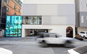 A modern hotel with a glass facade, a covered entrance, and a parking area. - alicehotel (Suwon)